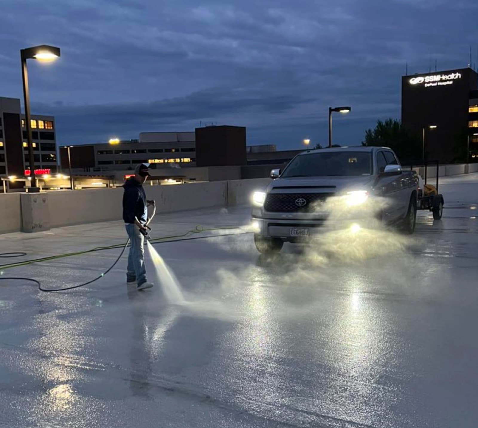 ATC crew pressure washing a parking deck at dusk